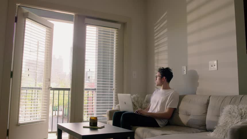 A man sitting on a couch typing on a laptop