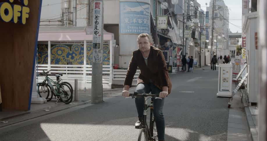 Man rides bicycle down city side street in japan