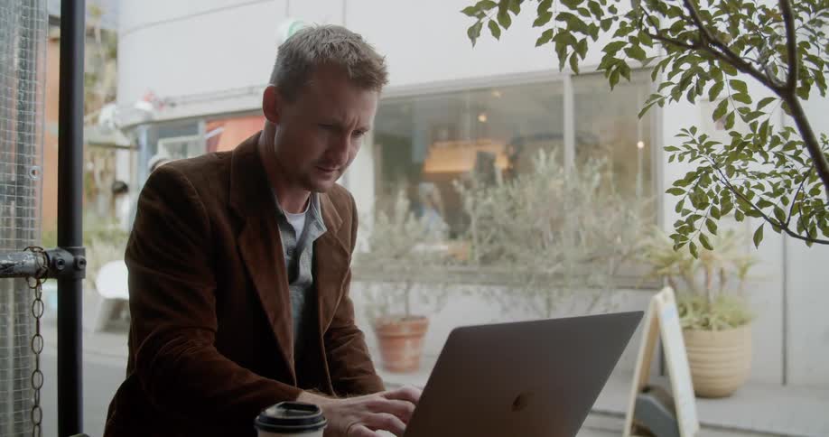 Man sitting at the table uses a laptop in the cafe