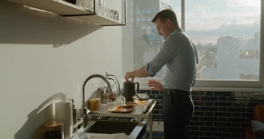 A man prepares a pot of tea in his kitchen