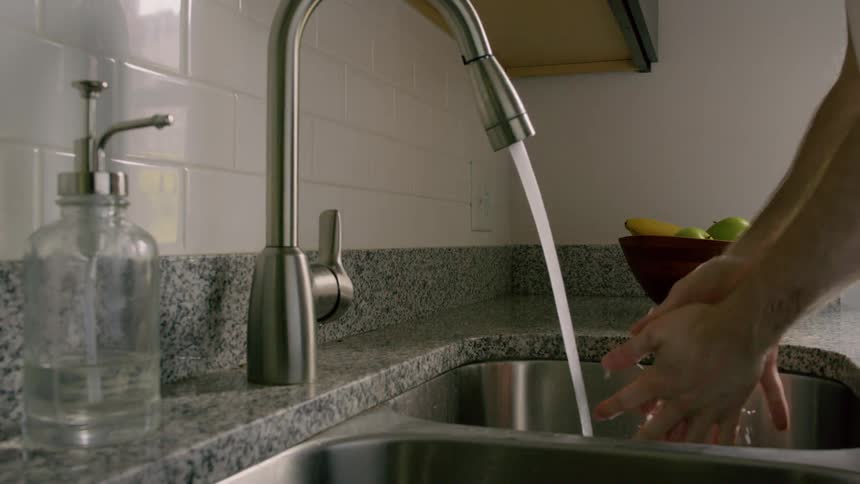 A man washes his hands in a kitchen sink