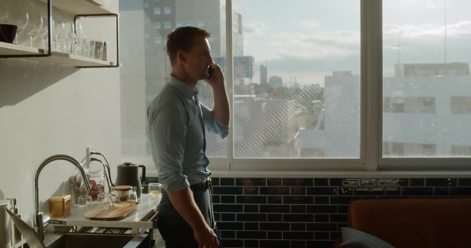 A person is talking on the phone while standing in the kitchen