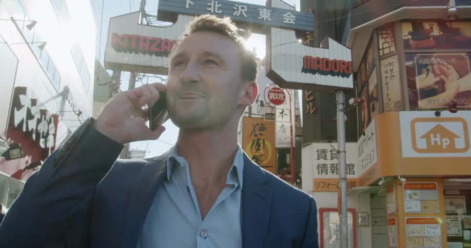A man standing on the streets talking on a cell phone