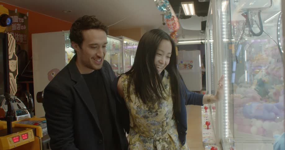 Couple playing on a claw crane in an arcade in japan