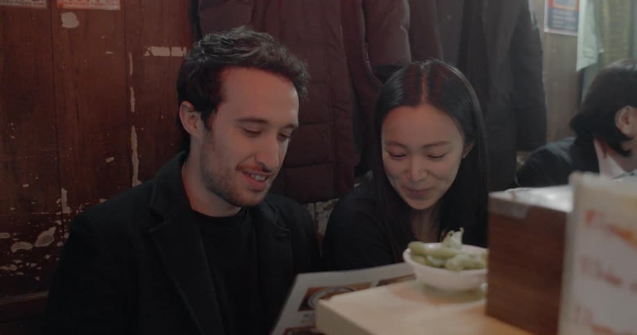 A man and woman look at a menu and order in a restaurant