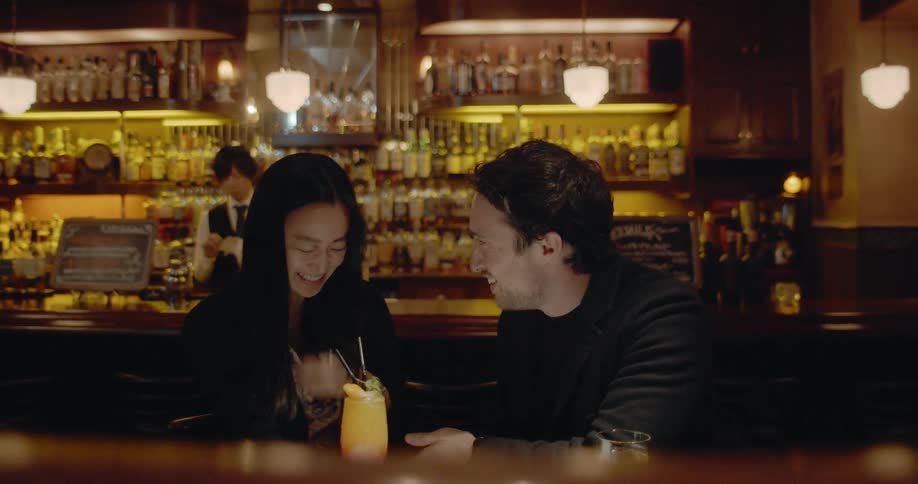 Asian woman and white man sitting at the table talk to each other in the bar