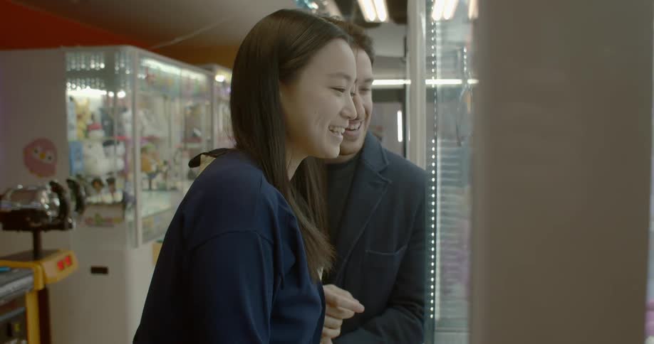 Two people playing a claw grabbing machine