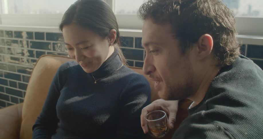 A man and woman sit on a couch together and look at a laptop