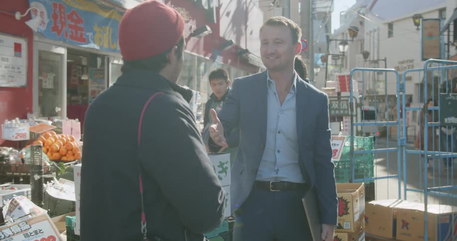 Friends talk and shake hands on a street market in city downtown
