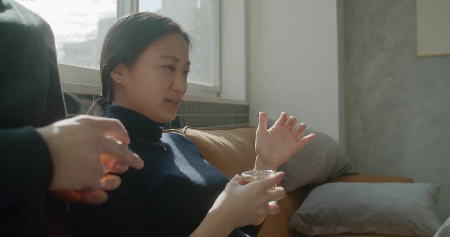Man and women drink hot beverage while watching laptop