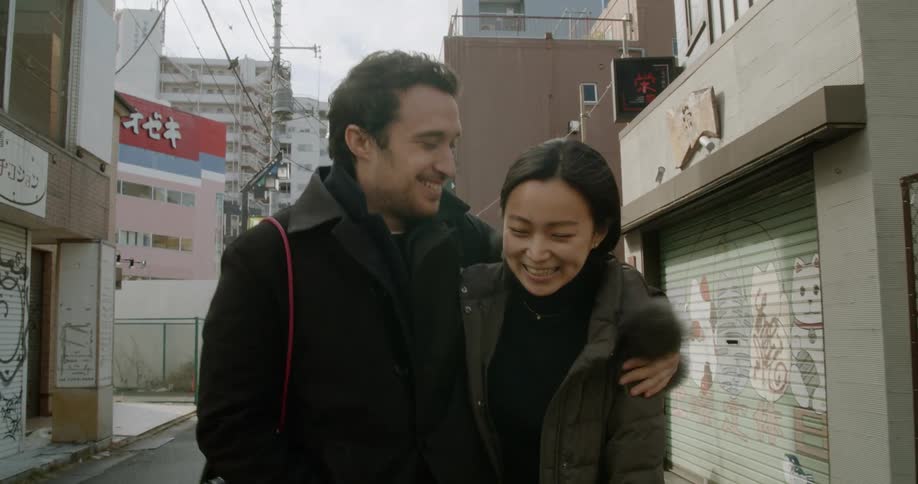 Couple walks along street smiling and hugging