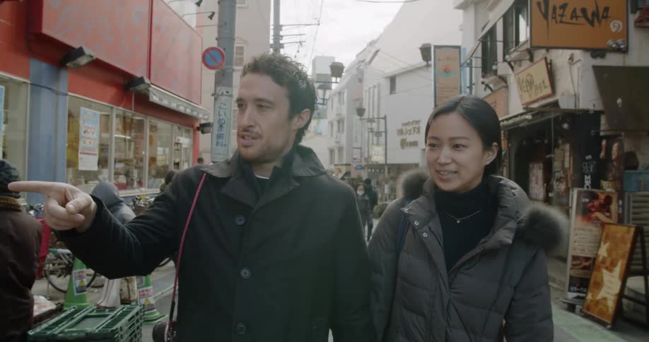 A man and woman walk down a city street while holding hands