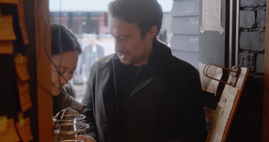 A man counts change at a store window as the woman he is with watches