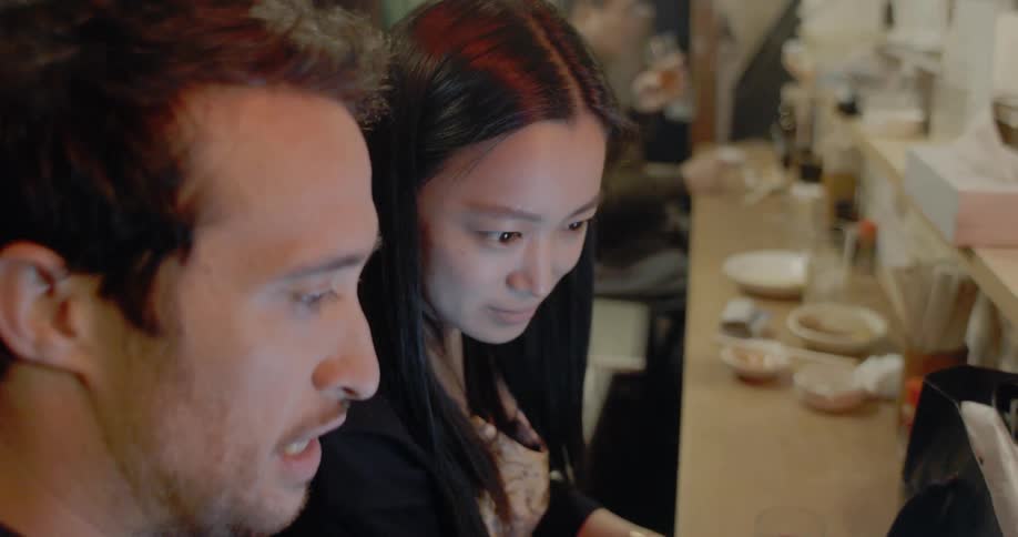 Couple check cell phone together and eat dinner at restaurant in japan