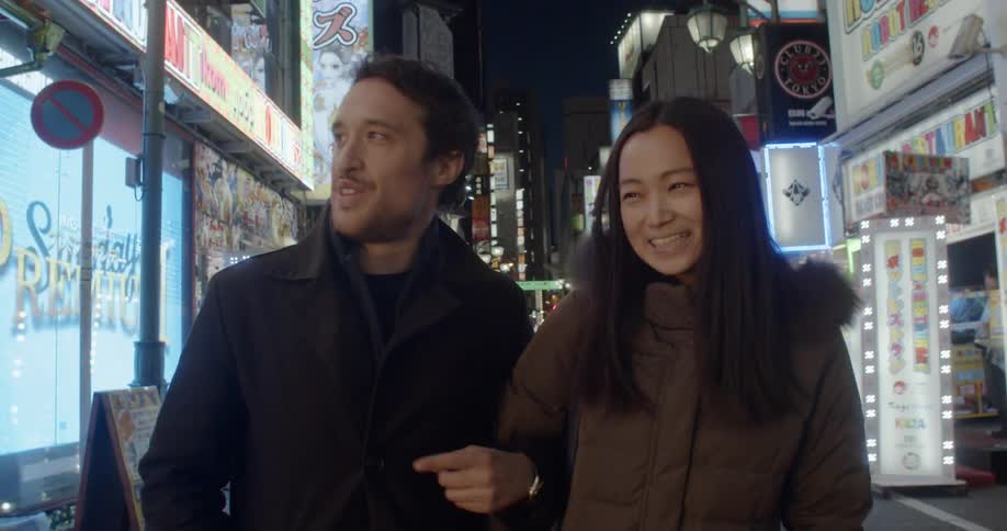 A man and woman holding hands and walking on a city street