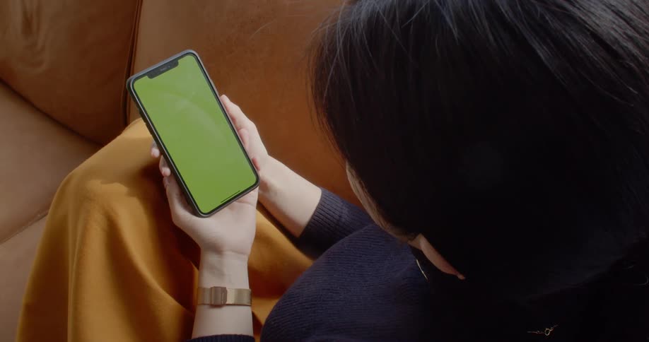 A woman sitting on a couch holding a smart phone