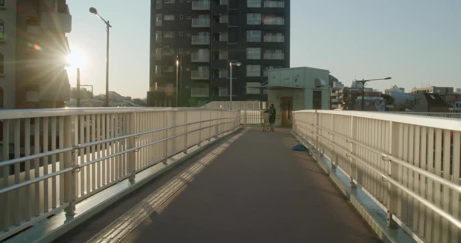 Man wearing shorts runs over a bridge on a sunny day
