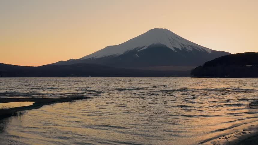 Man walking on lakeshore in front of mount fuji in japan