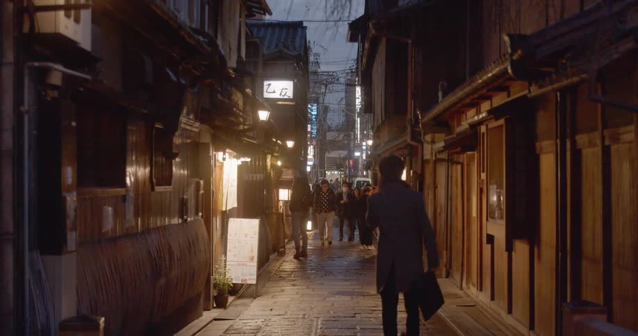 A man carrying a bag walks briskly down a narrow alley