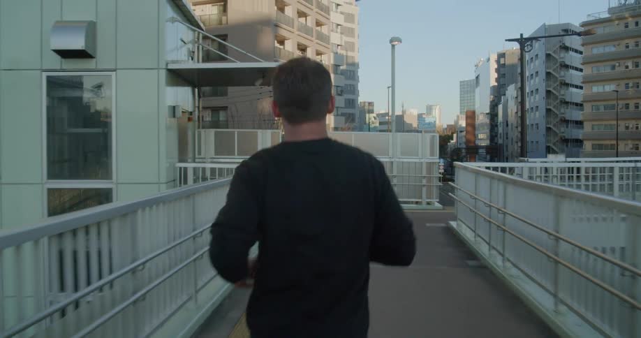 A man jogging on a pathway with buildings in the background