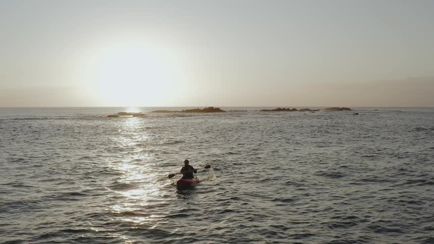 Person kayaking in the ocean at sunrise