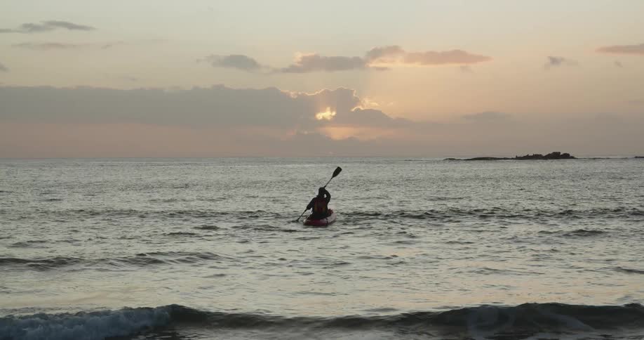A man kayaks out into the ocean