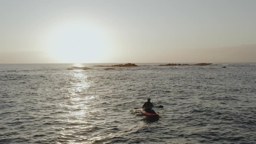 A man rows a kayak on choppy waves