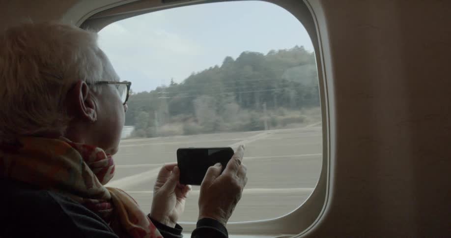 A woman takes pictures out the window of a train