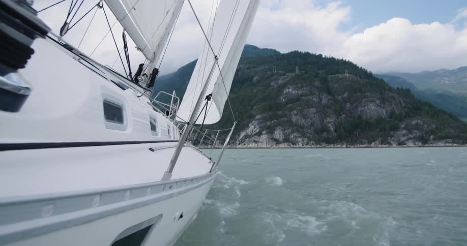 Close up of sail boat sailing towards small mountain in the distance