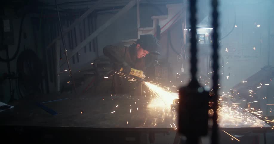 Man using power tool to cut metal on workshop