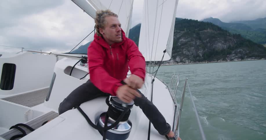 A man turns the winch handle on a sailing yacht