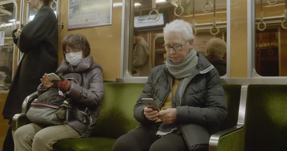 Woman riding subway checks phone while sitting
