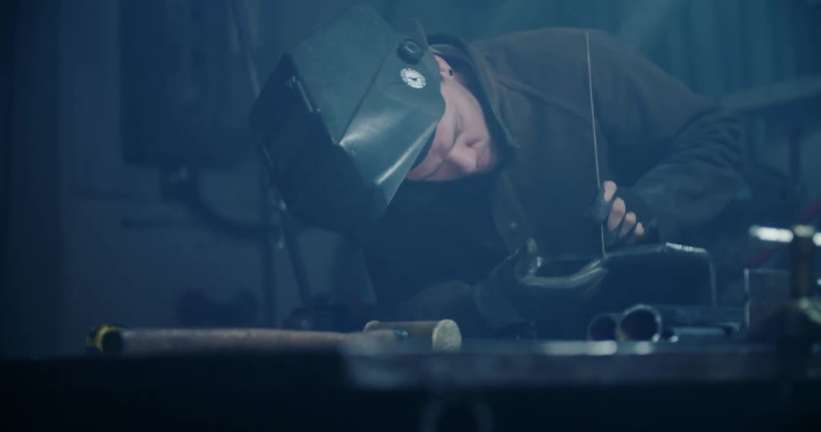 Worker measures metal piece on workbench at workshop