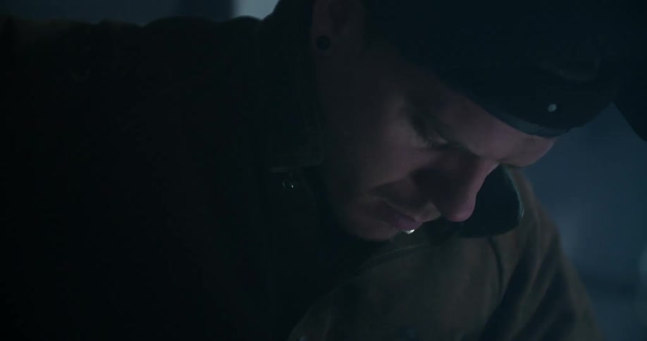 Man in winter coat and hat starts fire in dark