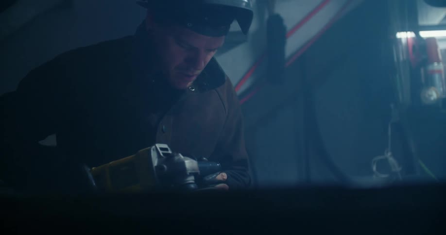 A man with a protective mask uses a power tool in a workshop