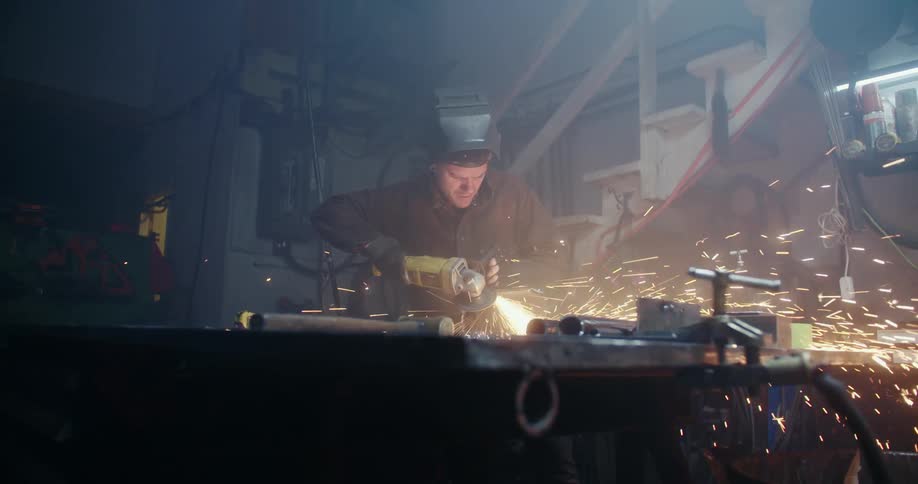Man uses power tool to cut metal on workshop