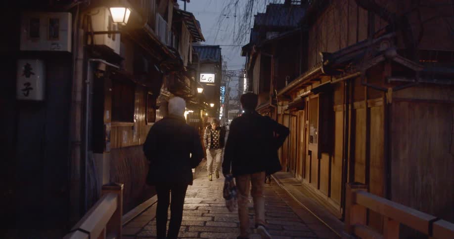 People walk down narrow cobblestone alley in asian city