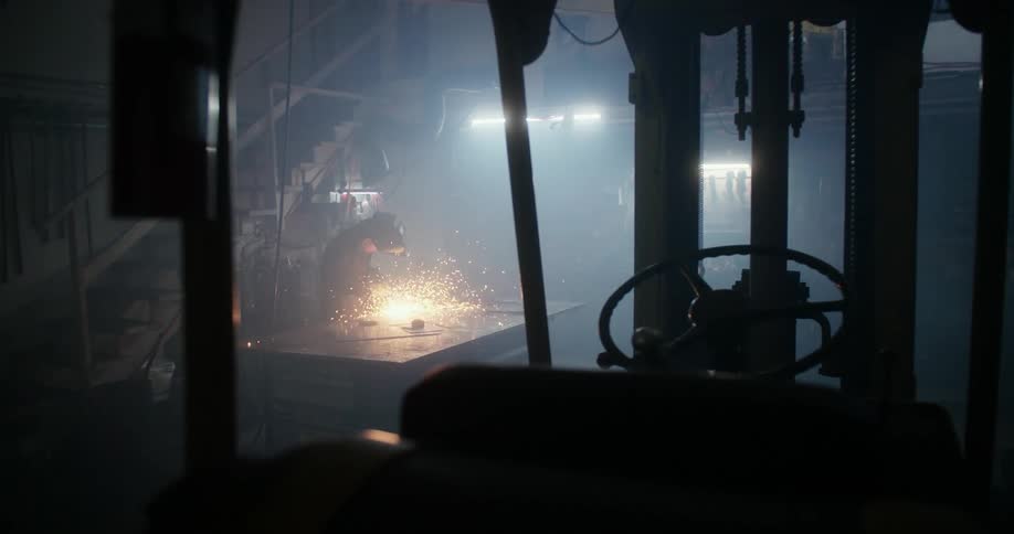 Sparks fly while a man uses a power tool in a workshop