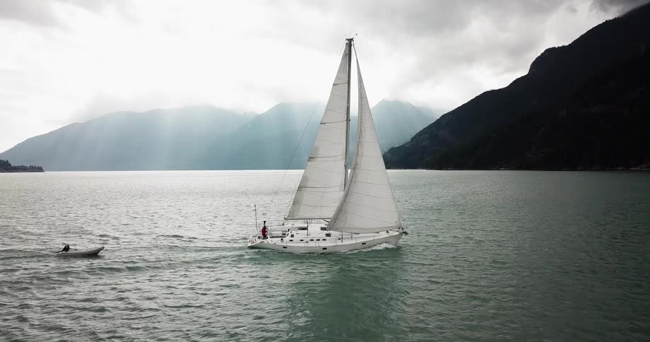A large white boat is sailing in the water near mountains