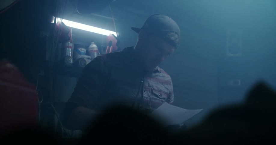 A man reads a piece of paper while standing in a dimly lit garage