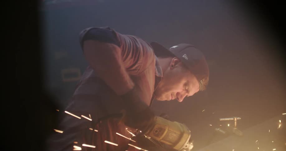 A man grinds metal with a tool