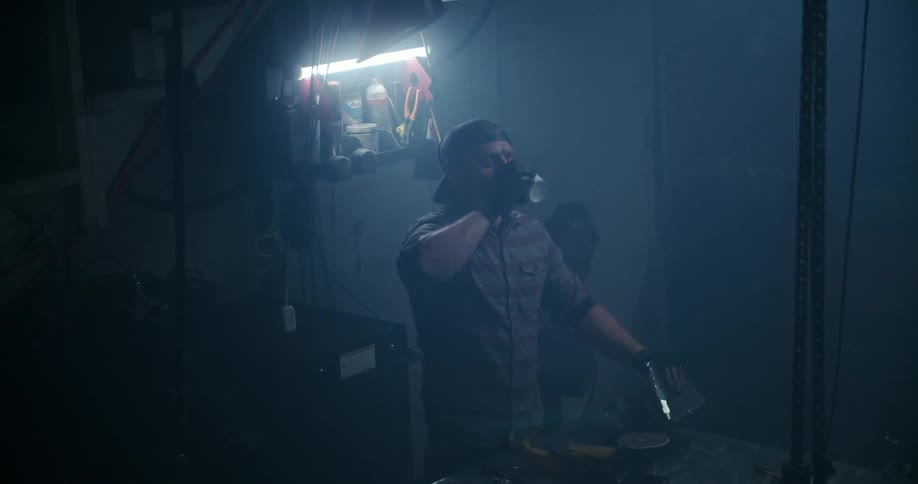 A young man drinks a beer in his work shop