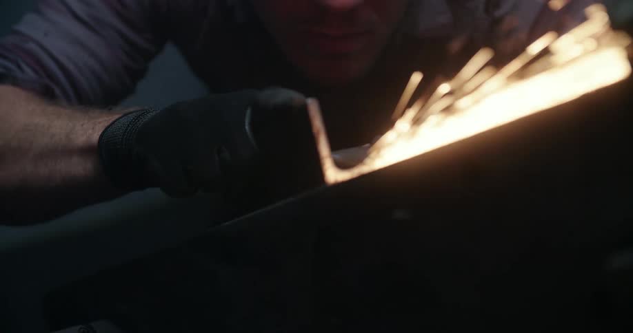 A man buffs a piece of metal with a power tool