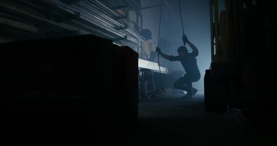 Worker wearing gloves lifts metal bars with workshop lift