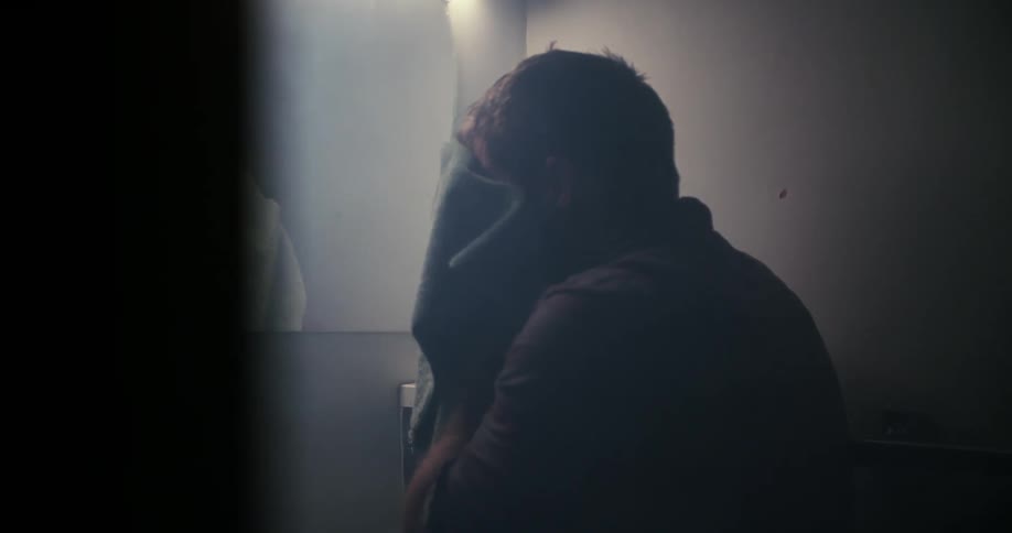 Man towel dries his face standing before mirror in bathroom