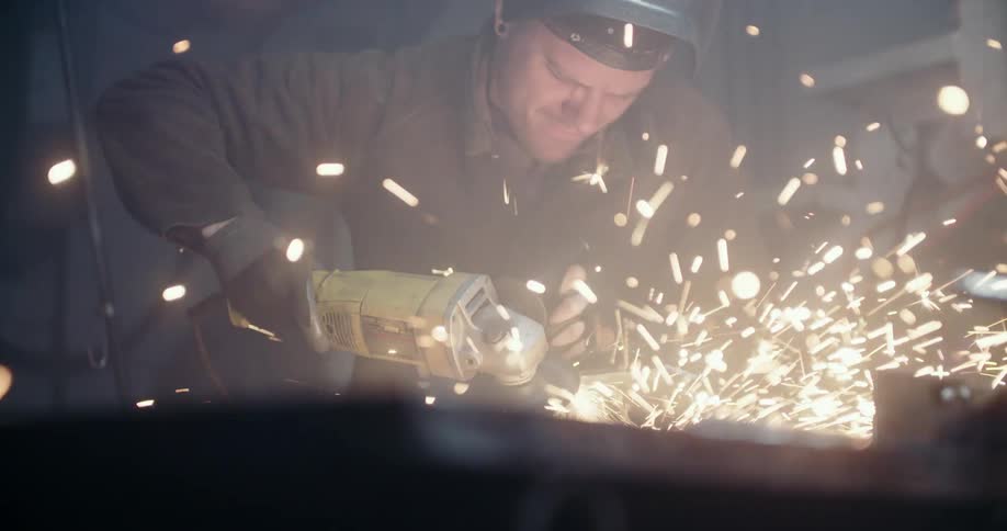 Worker cuts metal with power tool in workshop