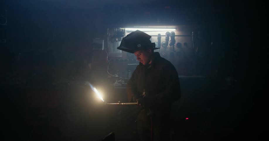 A man uses a blowtorch in his workshop