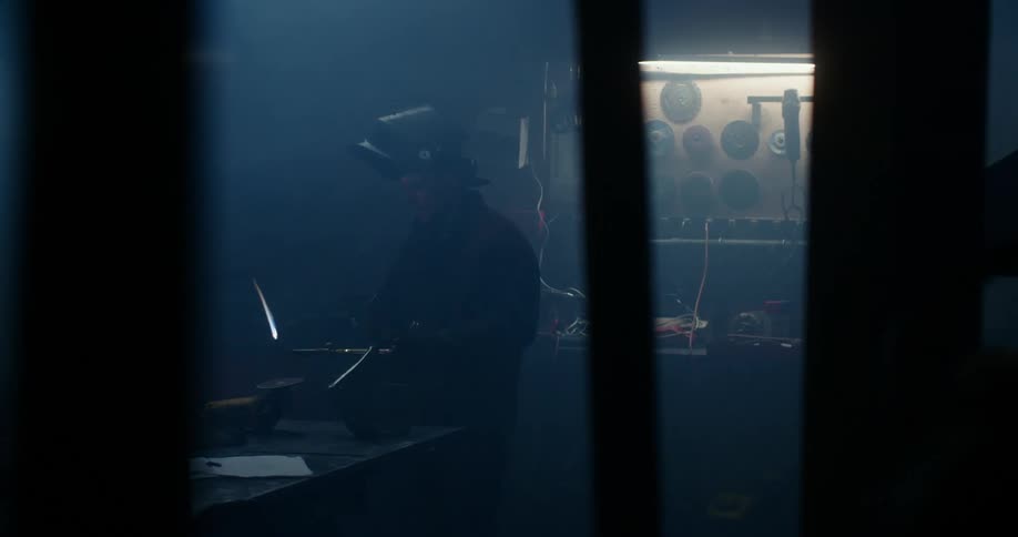 Man holds a burning torch as he stands near a workbench