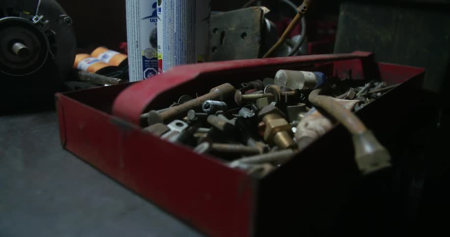 A metal box filled with bolts and other objects sits on a table top