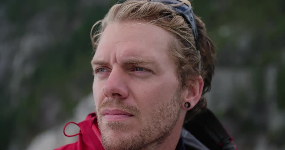 A man standing and staring off into the distance with trees in the background